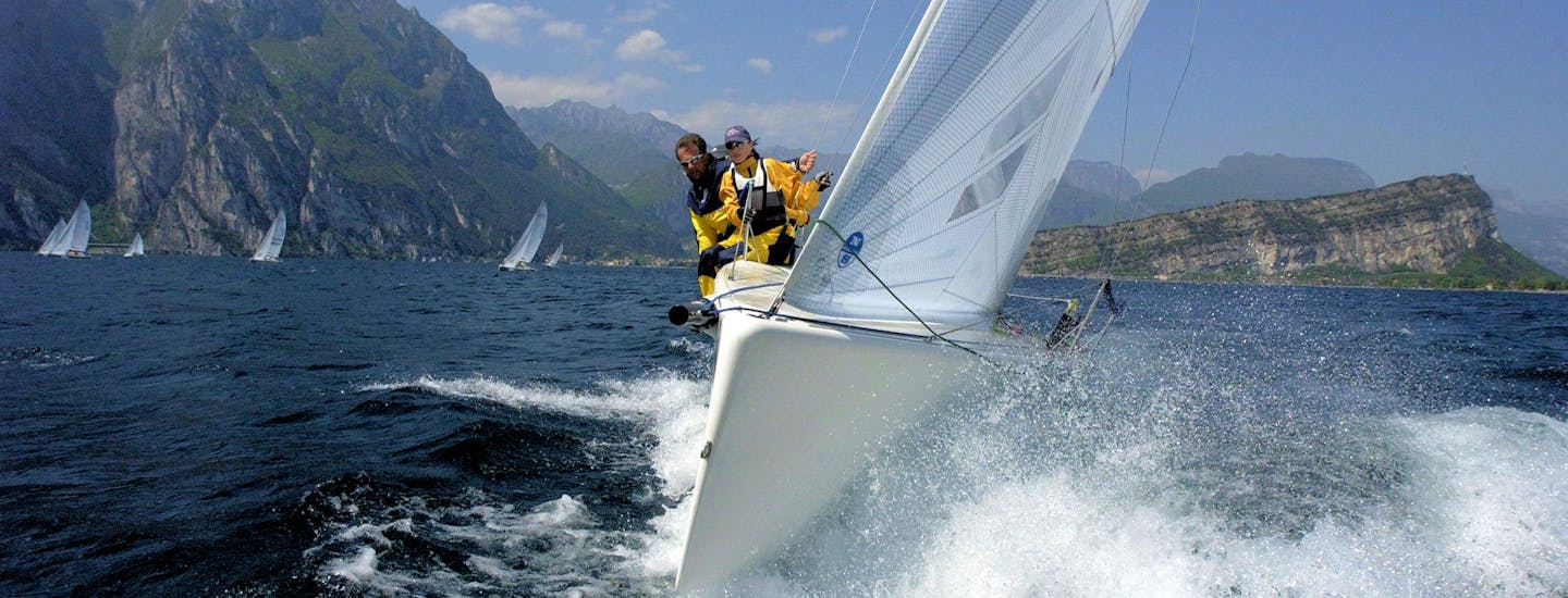 Skipper auf dem Gardasee zwischen Torbole und Riva del Garda im Hintergrund